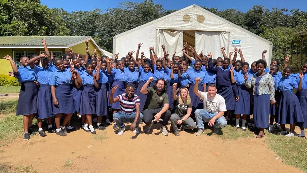 The team with a school group in Malawi, everyone with hands raised